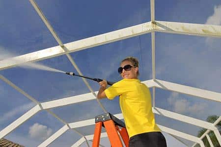 A Women Worker Washing conservatory with pressure washer pump in Essex UK