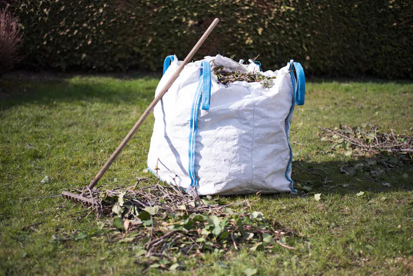 white bag filed with green waste in garden with leave remover tool in Essex UK