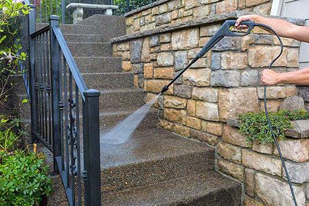 A professional washing leader in a garden with pressure washer in Essex UK