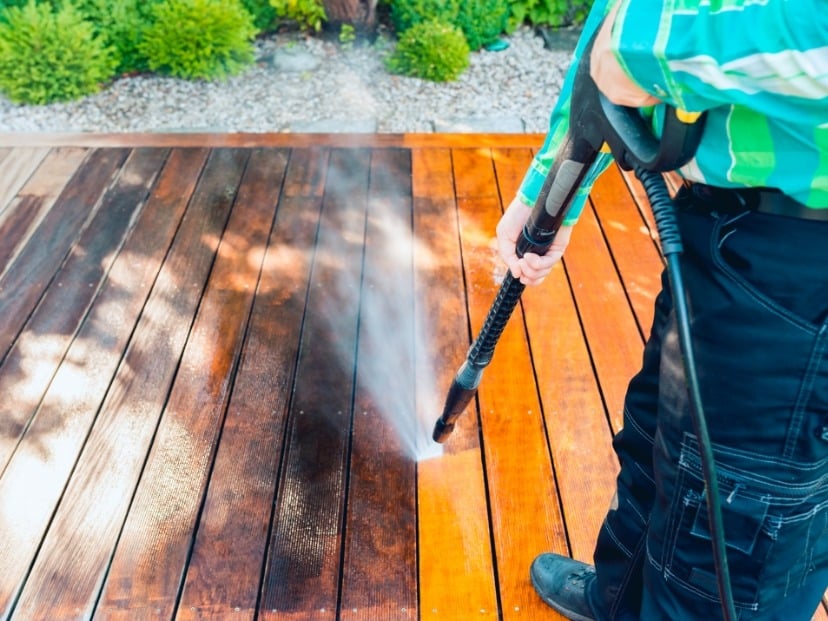 home and Garden Masters worker cleaning wooden patio with pressure washer somewhere in Essex County England UK